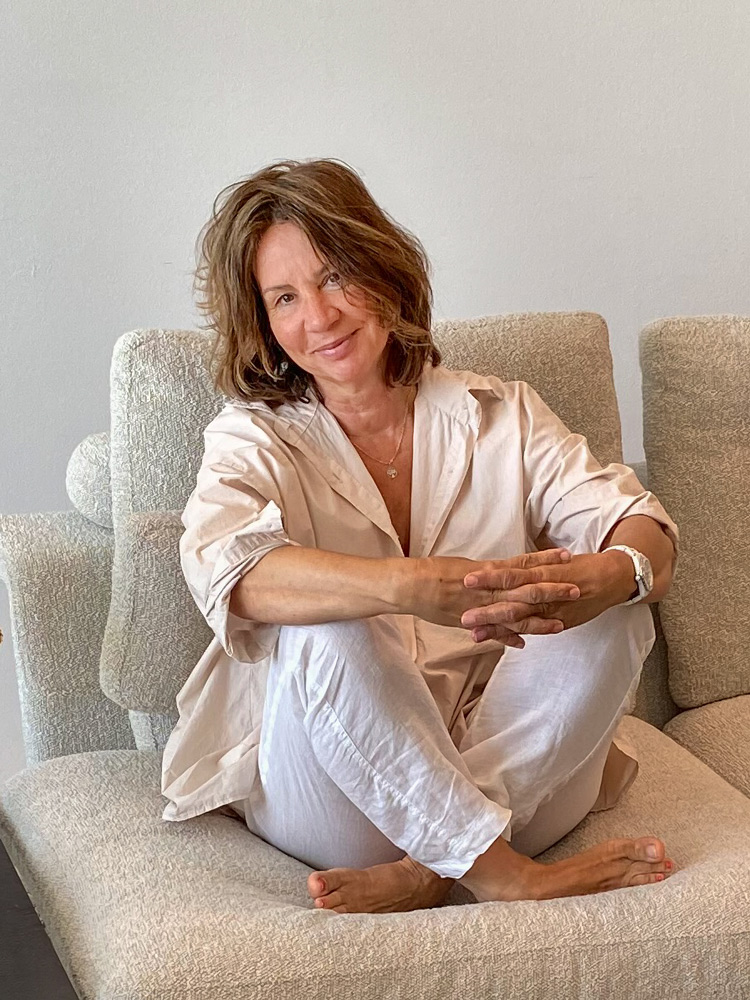 Eine lächelnde Martina sitzt entspannt auf einem hellen Sessel.